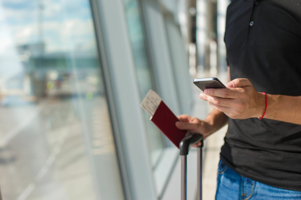 Man holding cell phone, passports and boarding passport at airport waiting the flight